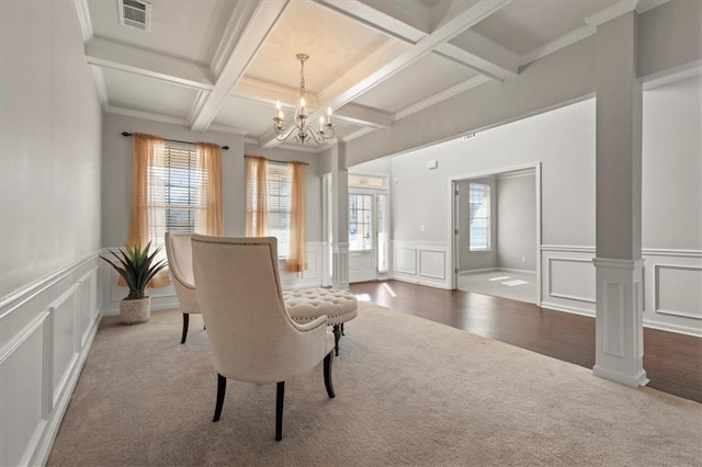 sitting room with coffered ceiling, ornate columns, carpet floors, a notable chandelier, and beam ceiling