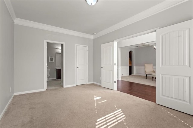 unfurnished bedroom featuring crown molding, ensuite bath, and carpet