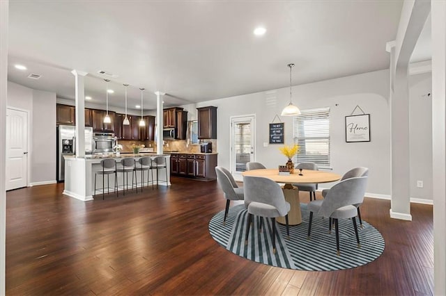 dining room with dark hardwood / wood-style floors and decorative columns