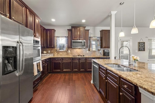 kitchen featuring sink, decorative light fixtures, appliances with stainless steel finishes, dark hardwood / wood-style floors, and light stone countertops