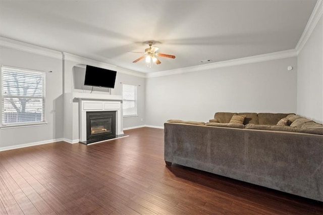 living room with dark wood-type flooring, ornamental molding, ceiling fan, and plenty of natural light