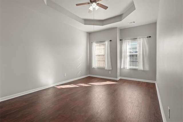 spare room featuring dark wood-type flooring, ceiling fan, and a tray ceiling