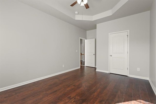 unfurnished bedroom featuring ceiling fan, dark hardwood / wood-style flooring, and a tray ceiling