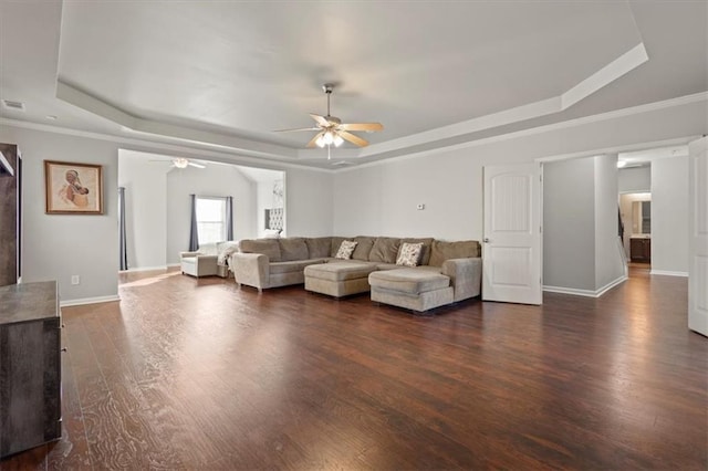 living room with ceiling fan, ornamental molding, dark hardwood / wood-style flooring, and a raised ceiling