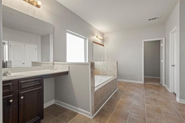 bathroom featuring vanity, tiled tub, and tile patterned flooring