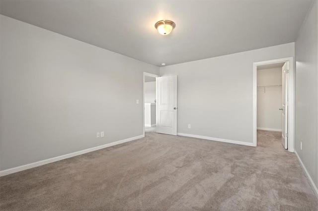 unfurnished bedroom featuring a spacious closet, light colored carpet, and a closet