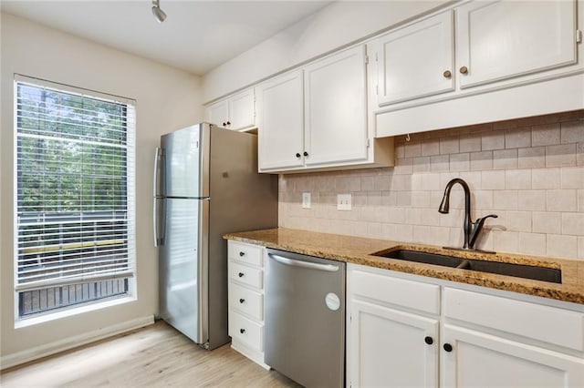 kitchen with dark stone counters, sink, white cabinetry, light hardwood / wood-style flooring, and stainless steel appliances