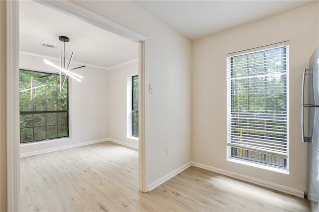 unfurnished room featuring light wood-type flooring, crown molding, and a notable chandelier