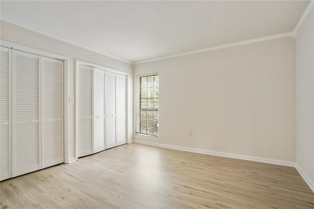 unfurnished bedroom featuring crown molding, light hardwood / wood-style flooring, and multiple closets