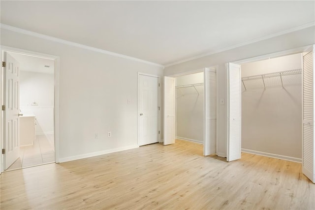 unfurnished bedroom featuring two closets, light hardwood / wood-style floors, ensuite bath, and crown molding