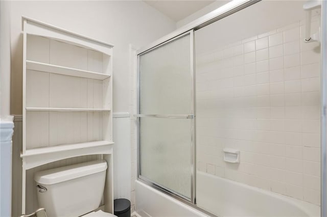 bathroom featuring combined bath / shower with glass door and toilet