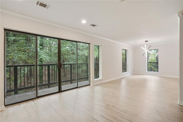 spare room featuring light wood-type flooring, ornamental molding, and an inviting chandelier