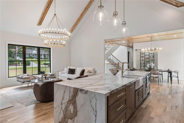 kitchen with pendant lighting, light wood-type flooring, a center island with sink, and sink