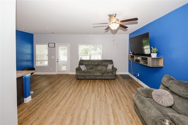 living area with wood finished floors, a ceiling fan, and baseboards