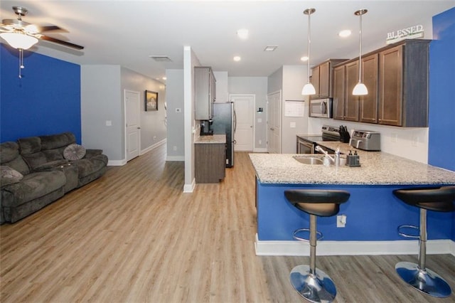 kitchen with stainless steel appliances, a sink, light wood-style floors, a ceiling fan, and recessed lighting