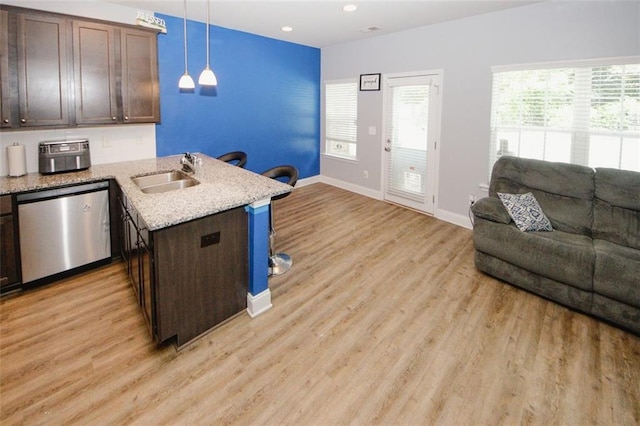 kitchen featuring dishwasher, a sink, open floor plan, dark brown cabinetry, and baseboards