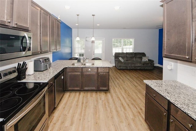 kitchen with stainless steel appliances, a peninsula, light wood-type flooring, a sink, and dark brown cabinetry
