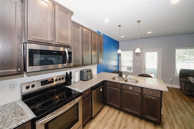 kitchen with stainless steel appliances, a sink, a peninsula, light wood-style flooring, and recessed lighting