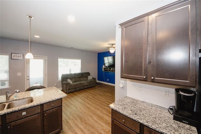 kitchen with a sink, plenty of natural light, dark brown cabinetry, light wood-type flooring, and recessed lighting