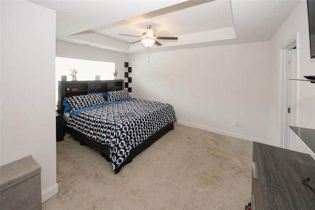 carpeted bedroom with a tray ceiling, baseboards, and ceiling fan