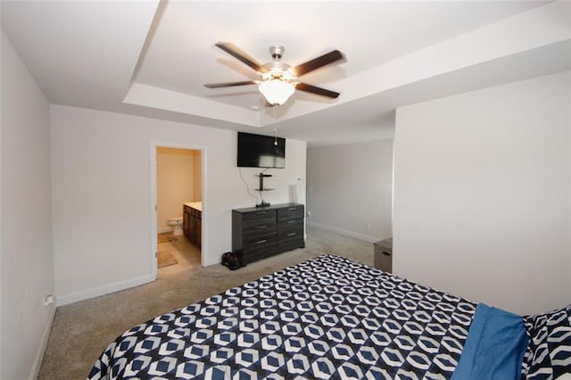 bedroom featuring light carpet, a raised ceiling, baseboards, connected bathroom, and ceiling fan