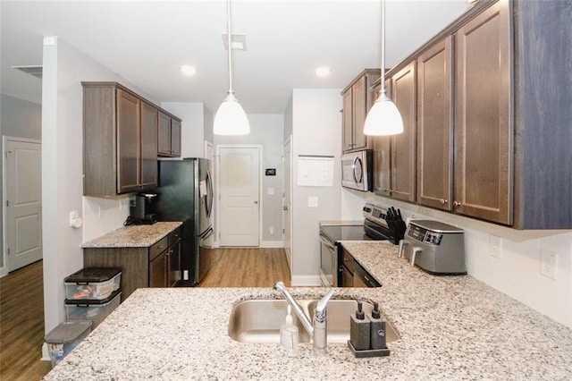 kitchen with stainless steel appliances, a sink, light wood-style flooring, backsplash, and light stone counters