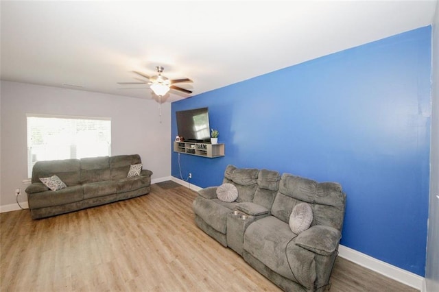 living room featuring baseboards, wood finished floors, and ceiling fan