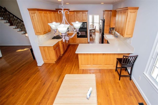2003 Hubbard Ct, Villa Rica, GA 30180 - kitchen with black appliances, a sink, a peninsula, decorative backsplash, and light wood-type flooring
