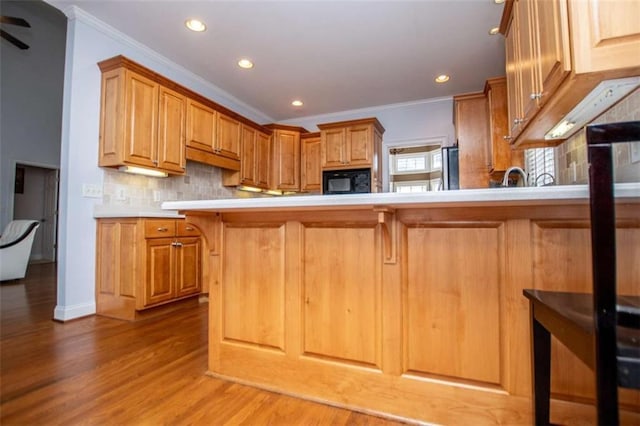 2003 Hubbard Ct, Villa Rica, GA 30180 - kitchen featuring ornamental molding, black microwave, light countertops, wood finished floors, and tasteful backsplash