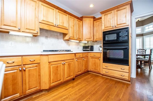 2003 Hubbard Ct, Villa Rica, GA 30180 - kitchen with black appliances, light countertops, light wood finished floors, backsplash, and ornamental molding