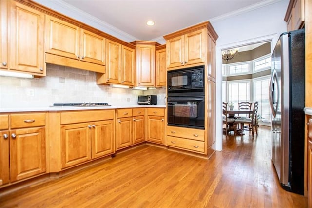 2003 Hubbard Ct, Villa Rica, GA 30180 - kitchen with black appliances, light wood-style floors, light countertops, crown molding, and a chandelier