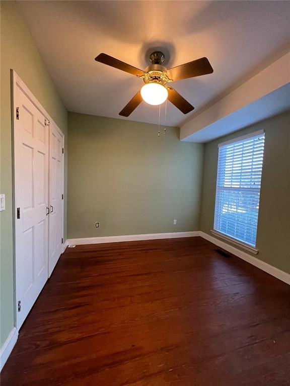 unfurnished bedroom with ceiling fan, a closet, and dark hardwood / wood-style floors