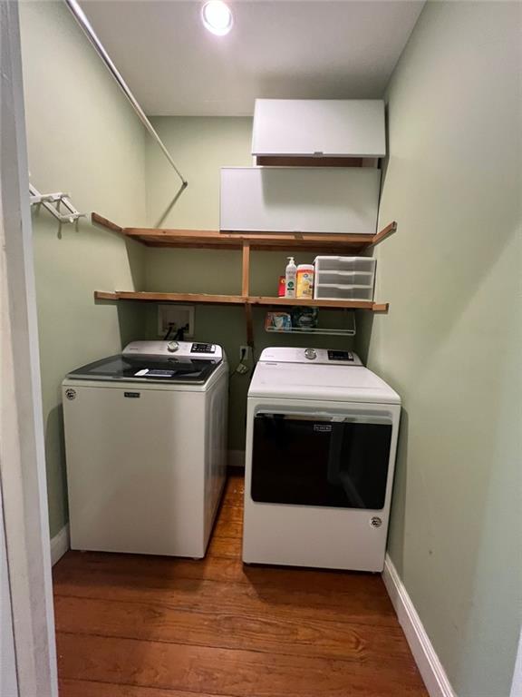 clothes washing area with separate washer and dryer and dark wood-type flooring