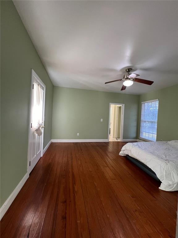 unfurnished bedroom with multiple windows, ceiling fan, and dark wood-type flooring