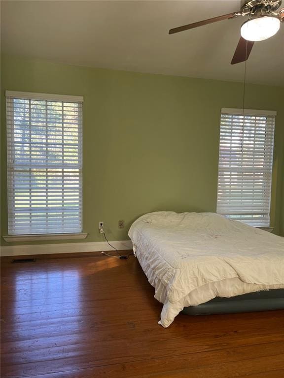 bedroom with multiple windows, ceiling fan, and dark hardwood / wood-style floors