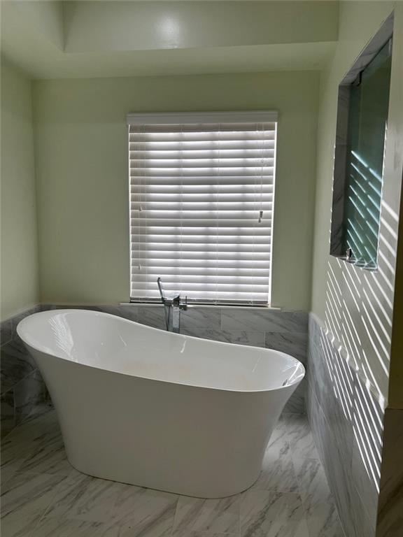 bathroom featuring a tub to relax in and tile walls