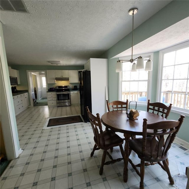 dining room with visible vents, a textured ceiling, lofted ceiling, and baseboards