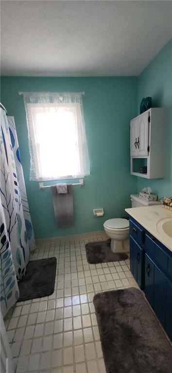 full bathroom featuring a textured ceiling, toilet, vanity, and a shower with curtain