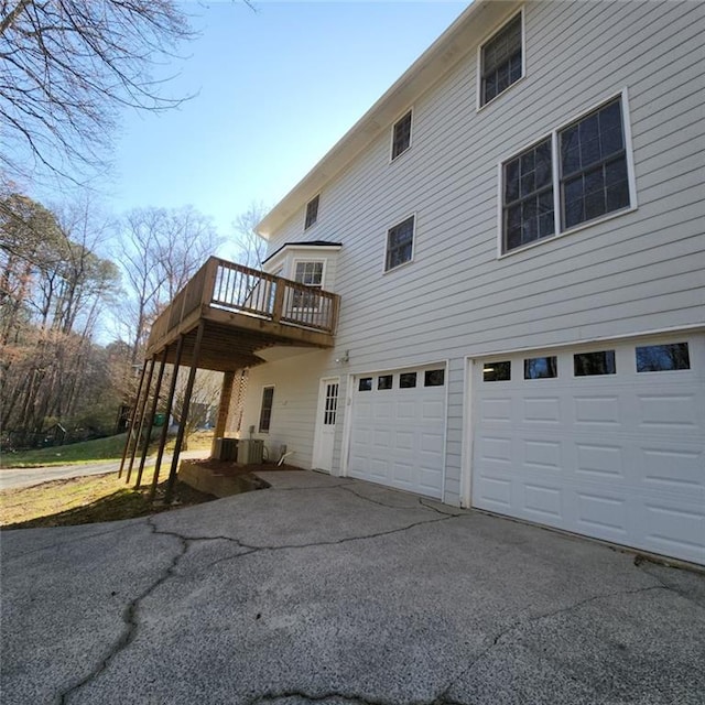 view of side of home with a deck, aphalt driveway, and an attached garage