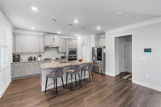 3717 Blue Goose Ln, Loganville, GA 30052 - kitchen with appliances with stainless steel finishes, ornamental molding, a breakfast bar, an island with sink, and tasteful backsplash