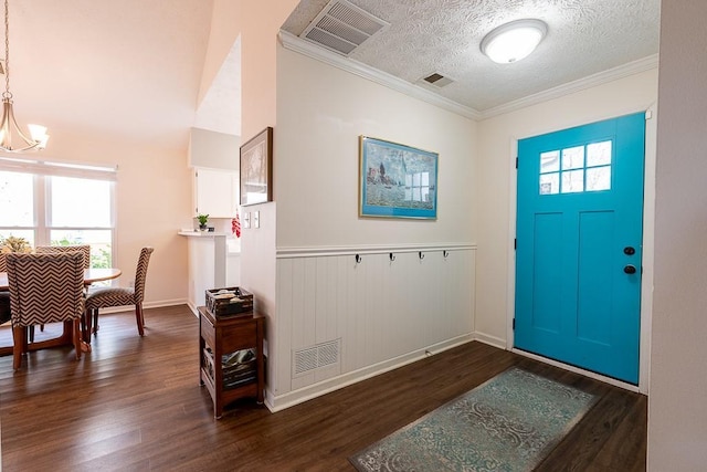 entrance foyer featuring an inviting chandelier, ornamental molding, a healthy amount of sunlight, and dark hardwood / wood-style flooring