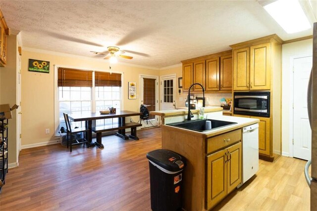 312 Henderson Mill Rd, Mansfield, GA 30055 - kitchen featuring built in microwave, dishwasher, an island with sink, light wood-style flooring, and a sink