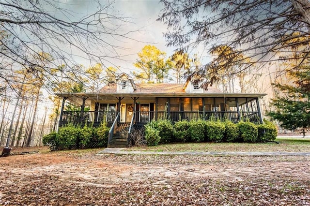 view of front of property with a sunroom, stairway, and covered porch