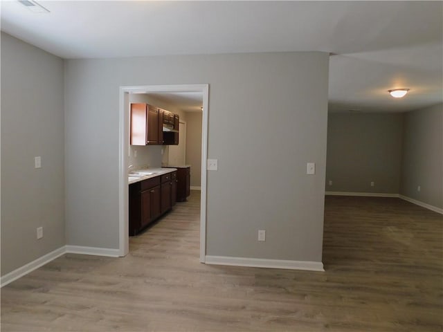 interior space with dark brown cabinets, sink, and light hardwood / wood-style flooring