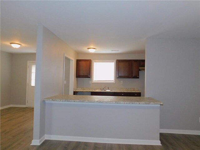 kitchen with dark wood-type flooring, sink, and light stone countertops