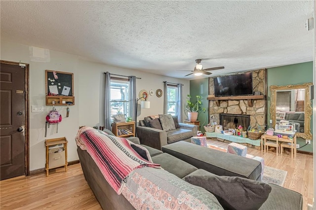 2642 Bridgehampton Rd SW, Marietta, GA 30064 - living area featuring a fireplace, light wood-style flooring, a textured ceiling, a ceiling fan, and baseboards