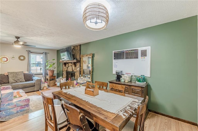 2642 Bridgehampton Rd SW, Marietta, GA 30064 - dining room with a textured ceiling, a stone fireplace, wood finished floors, and ceiling fan