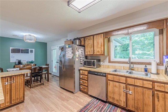 2642 Bridgehampton Rd SW, Marietta, GA 30064 - kitchen featuring stainless steel appliances, a sink, light countertops, light wood-style floors, and brown cabinetry