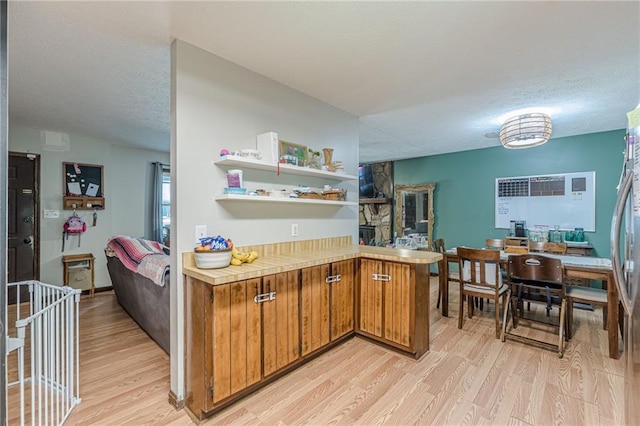 2642 Bridgehampton Rd SW, Marietta, GA 30064 - kitchen with light wood-type flooring, brown cabinetry, light countertops, a textured ceiling, and a peninsula