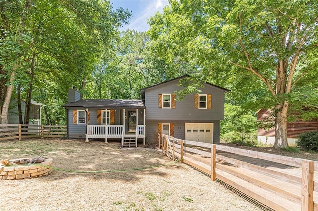 2642 Bridgehampton Rd SW, Marietta, GA 30064 - tri-level home featuring dirt driveway, an attached garage, a chimney, an outdoor fire pit, and a porch